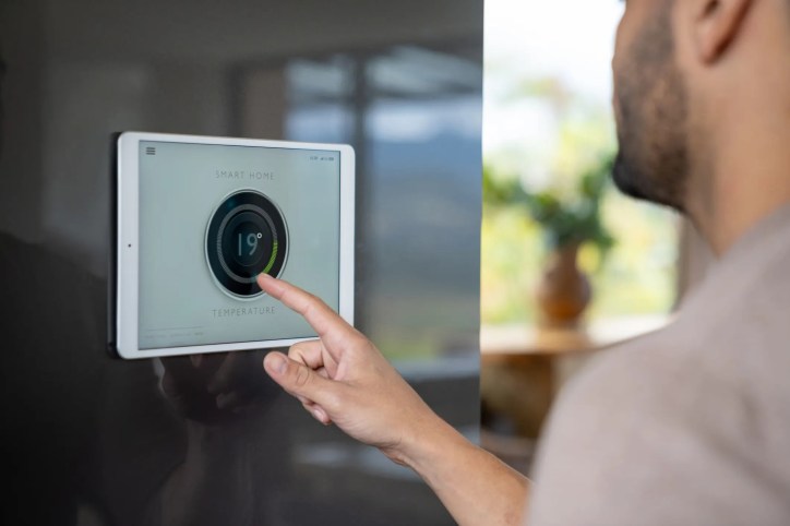 HVAC digital thermostat being adjusted by man.
