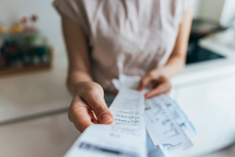 Hands holding receipts to analyze final balance.