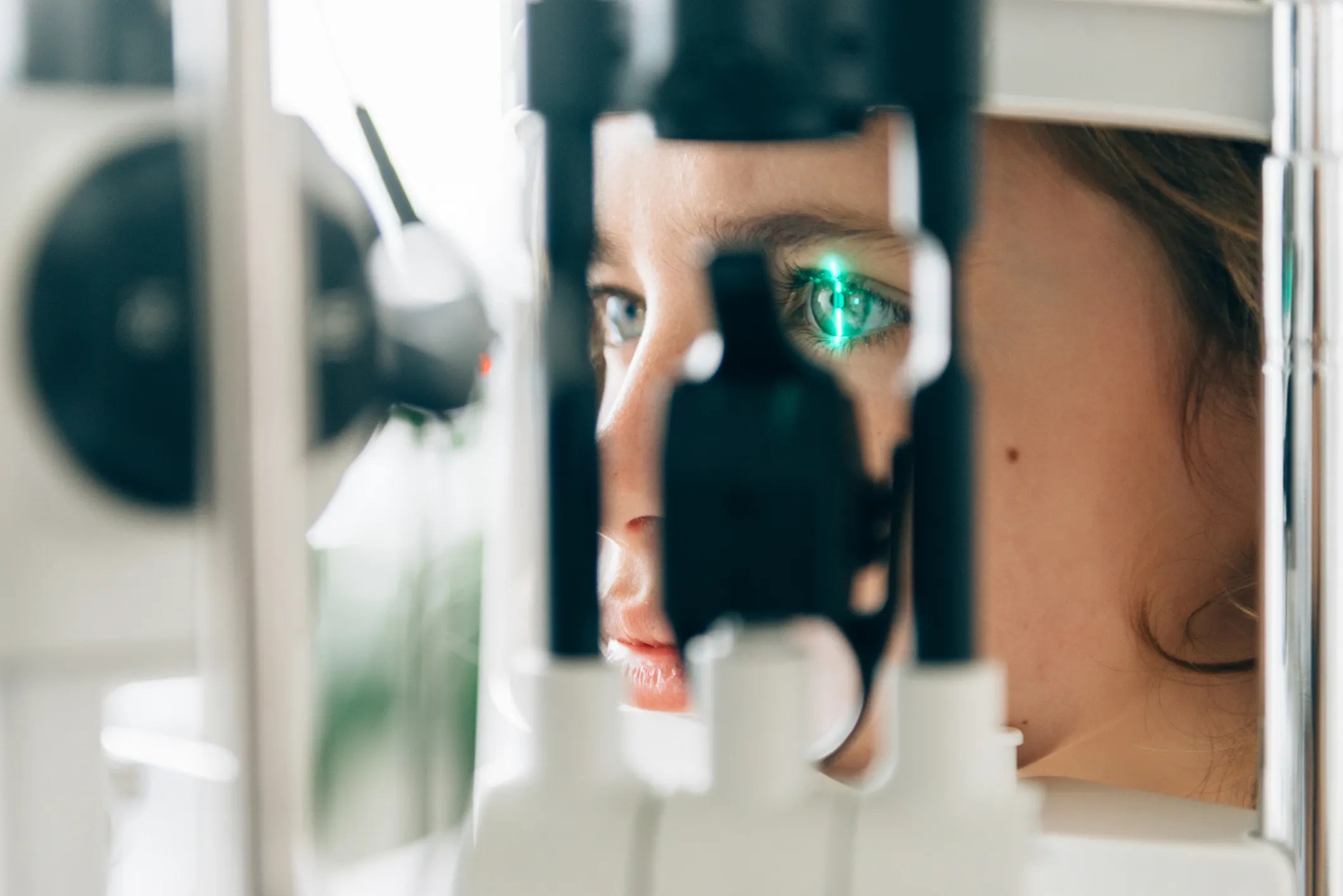 Girl at eye checkup, looking into the finest standard ophthalmic equipment.