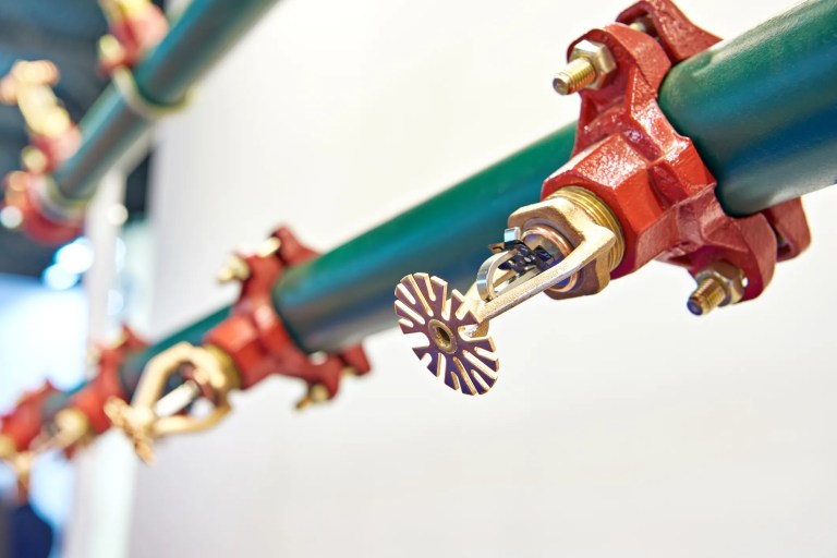 Close up of red and green sprinklers as part of building fire protection system.