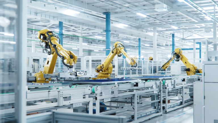 Three yellow arms working in automation at factory.