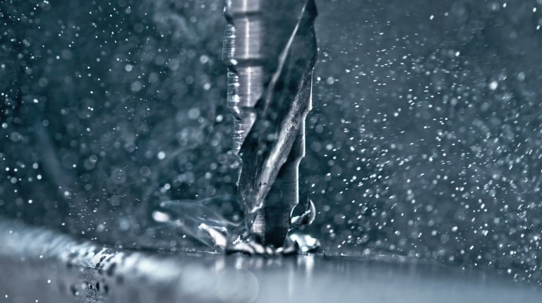 Drill bit cutting into metal close up.