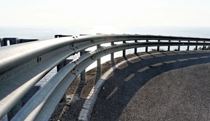 Metal guard rail curving beneath sky.