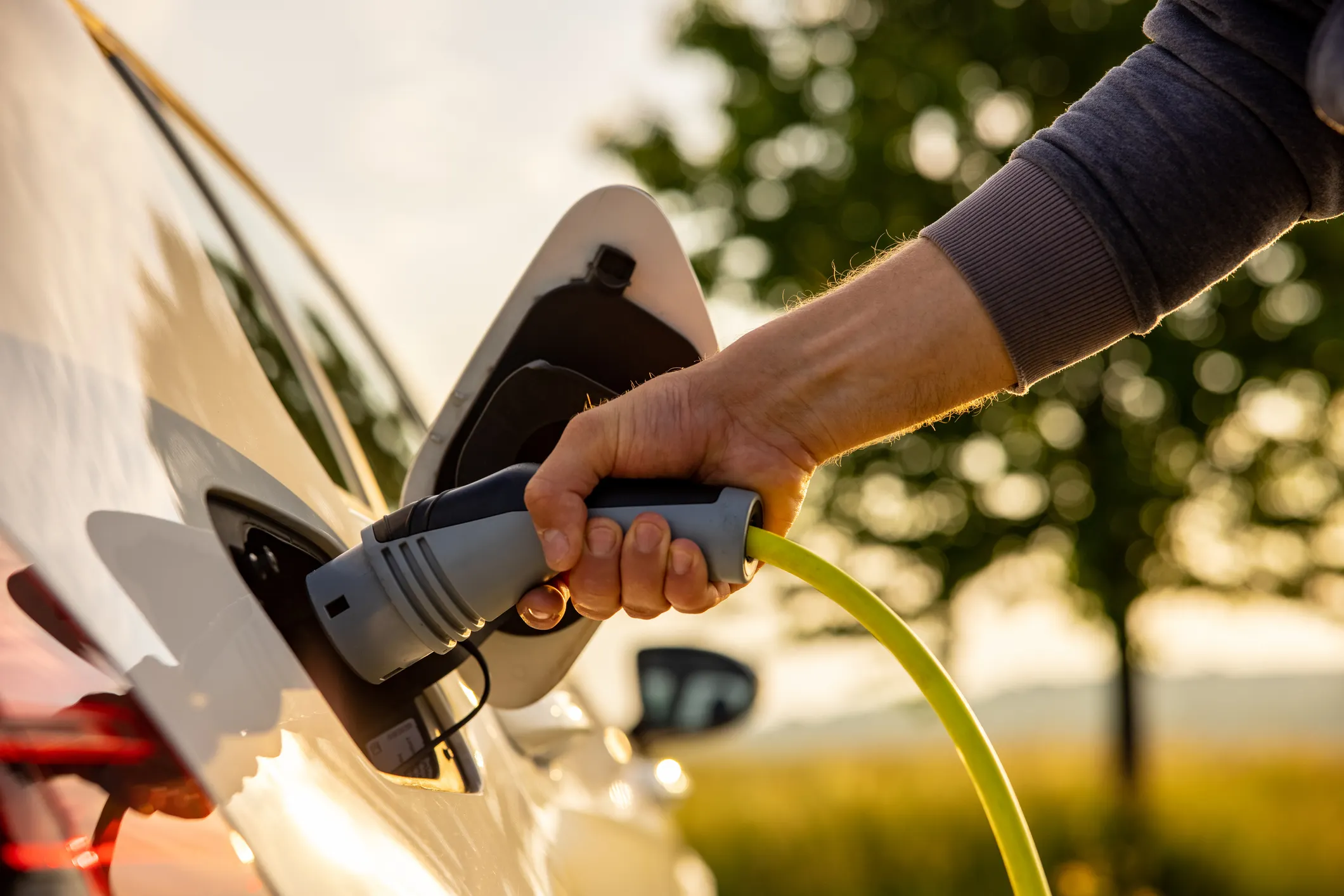 Hand inserting charger into plug-in hybrid car following SAE J 1711 emissions with green background