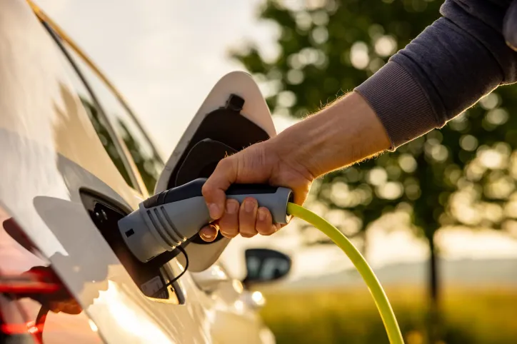 Hand inserting charger into plug-in hybrid car following SAE J 1711 emissions with green background