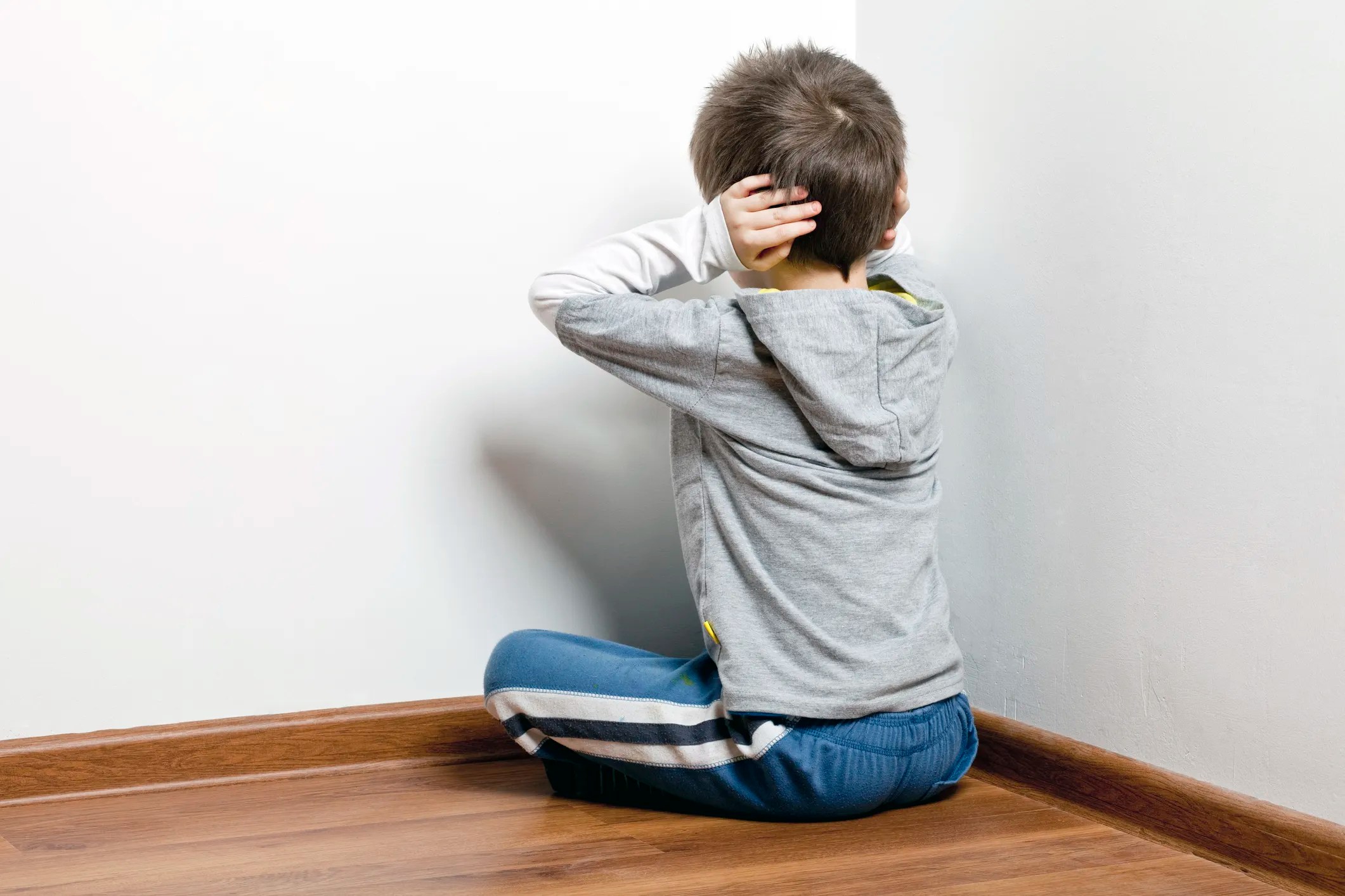 Boy covering ears in corner of room because drywall hasn't been tested for acoustics.