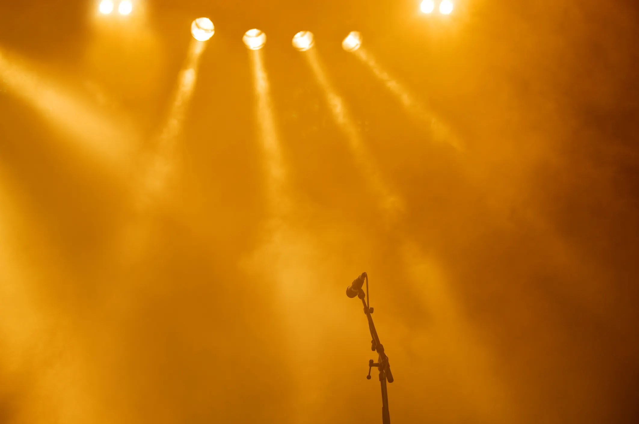 Yellow ANSI E1.23 entertainment fog on stage with lights and mic.