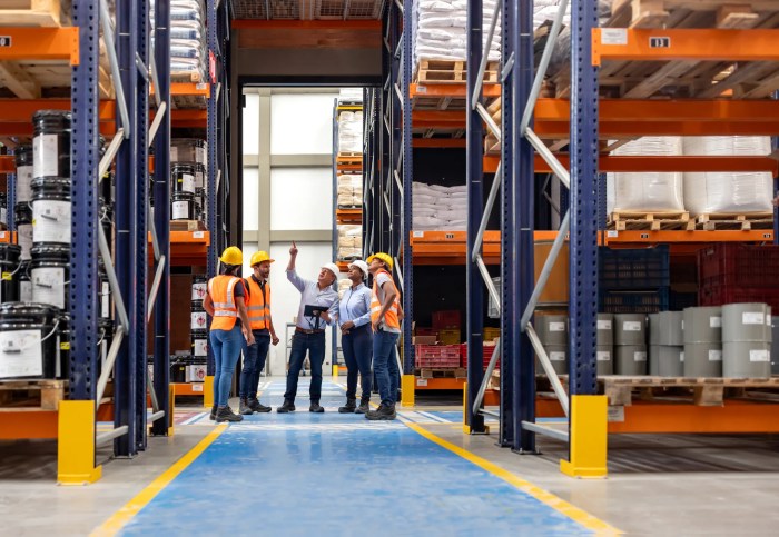 Foreman talking to workers in warehouse to set behavioral based safety with orange.