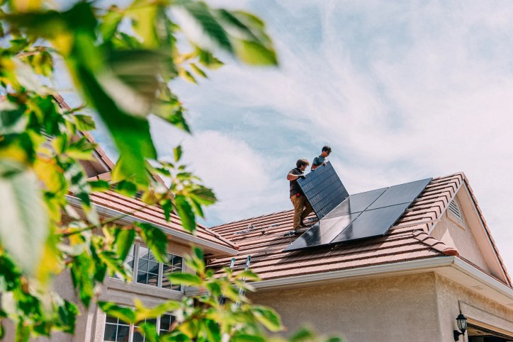 Solar panels being installed by two men on roof of Southwest home.