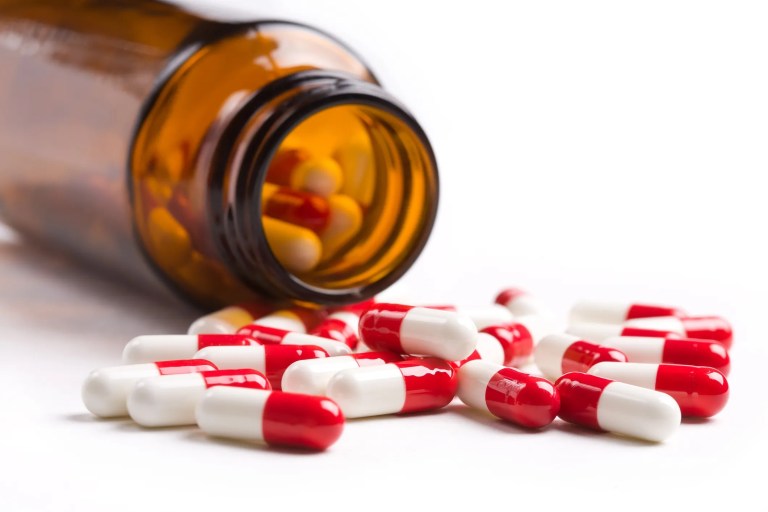 Spilled antibiotic bottle with red and white pills