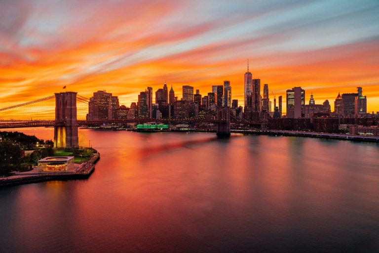 The East river at sunset, with the Brooklyn Bridge and Manhattan skyline.