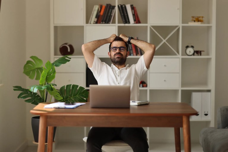Man frustrated at computer on wooden desk after falling victim to cybercrime