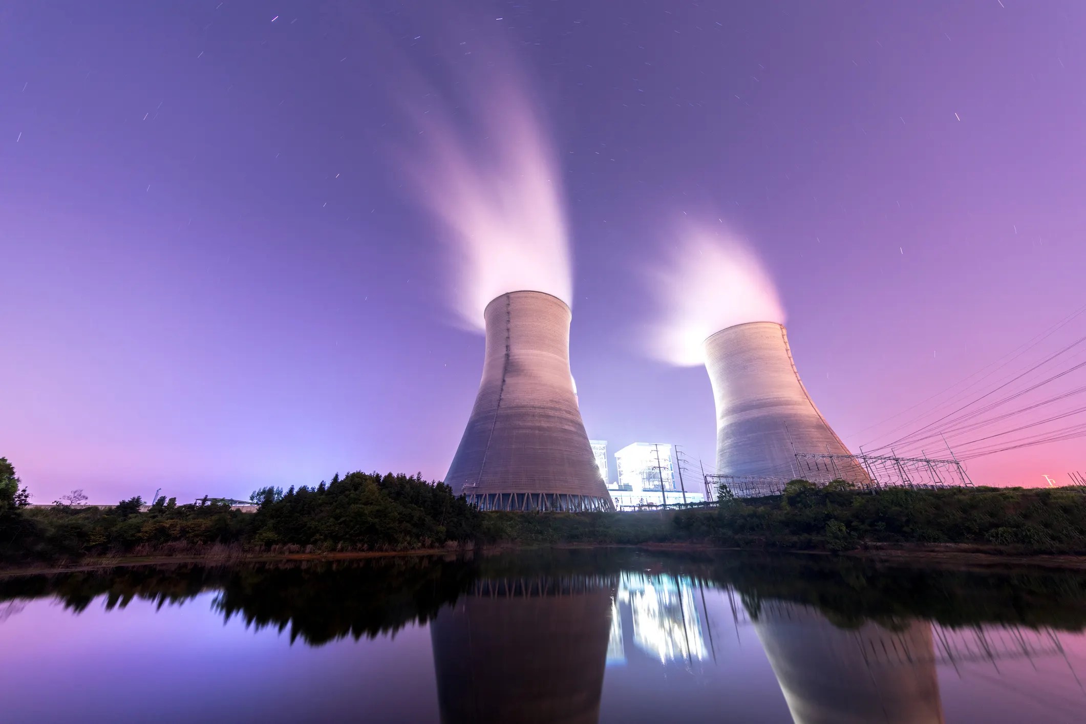 Nuclear cooling towers running at night in purple sky