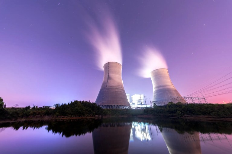 Nuclear cooling towers running at night in purple sky