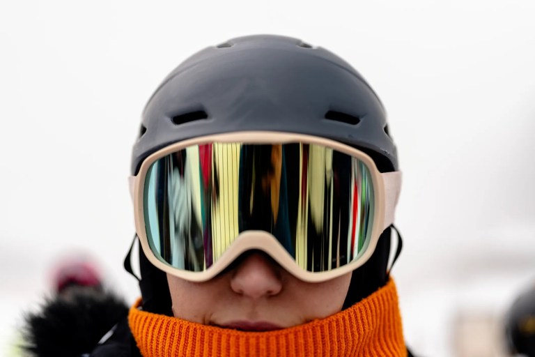 Woman wearing ASTM F659 ski goggles under gray helmet in winter
