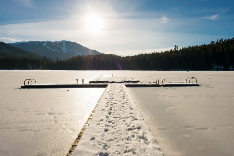 Sun shining on snow covered lake dock, leading to snow glare