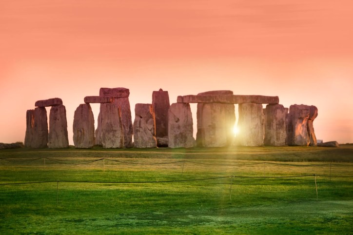 Stonehenge above the green grass and beneath sunset