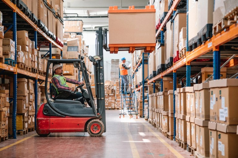 Worker on forklift while lifting box in warehouse