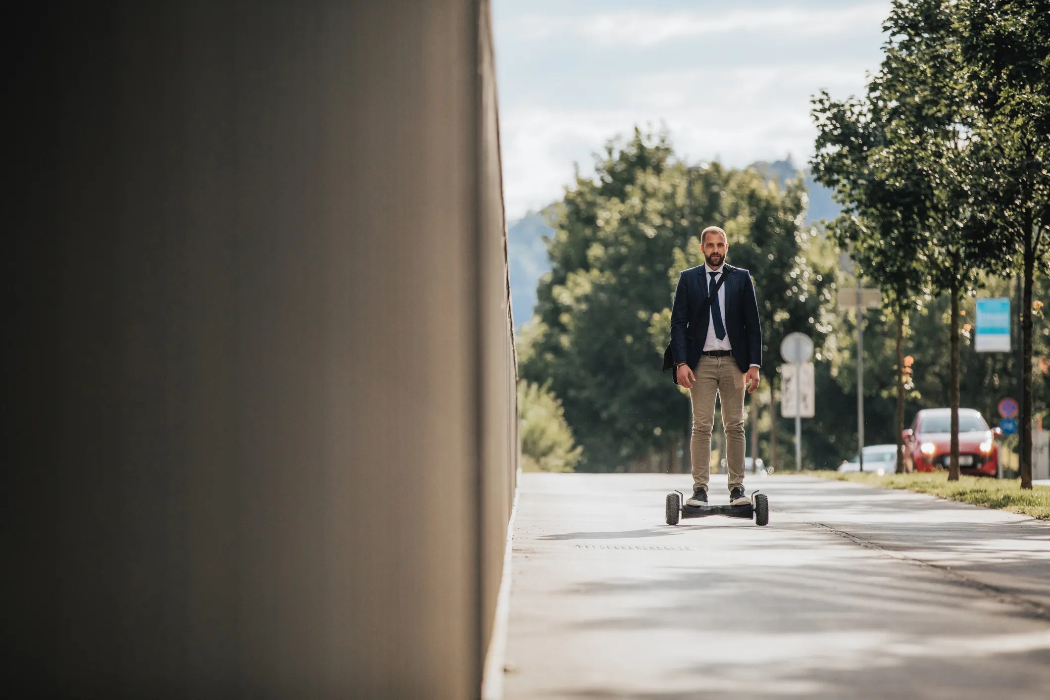 Man in suit riding hoverboard on sidewalk