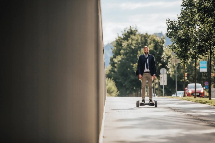 Man in suit riding hoverboard on sidewalk