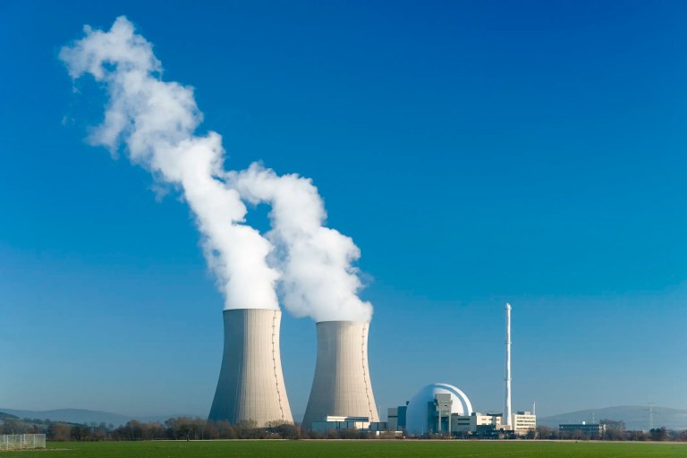 Nuclear power cooling towers smoking beneath blue sky
