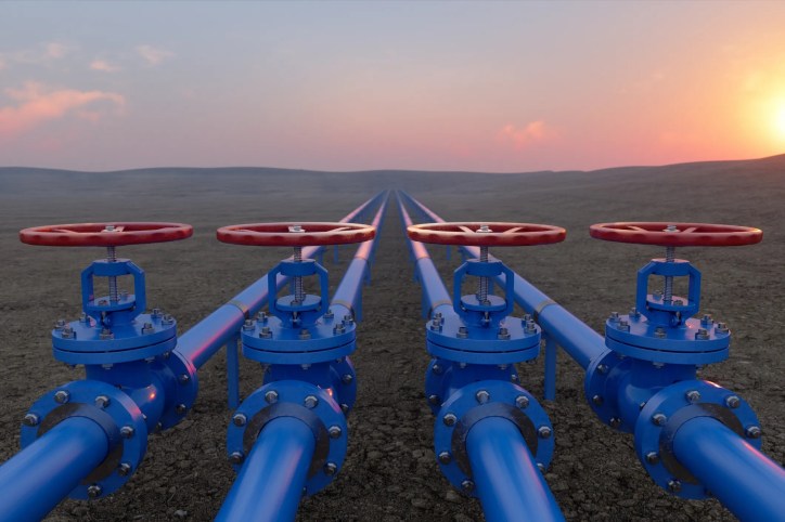 4 blue pipes with red valves to control petroleum under desert sun.