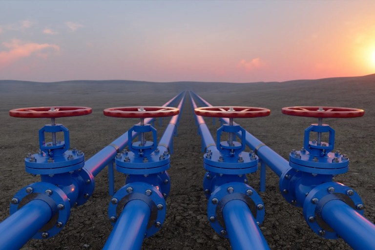 4 blue pipes with red valves to control petroleum under desert sun.