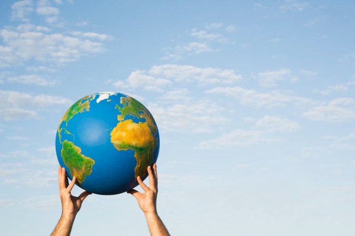 Hands holding globe outside to the sky in honor of Earth Day