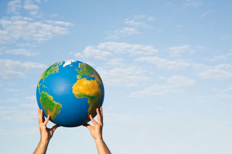 Hands holding globe outside to the sky in honor of Earth Day