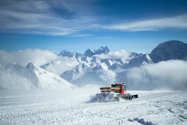 Snowcat grooming snow with mountains in background