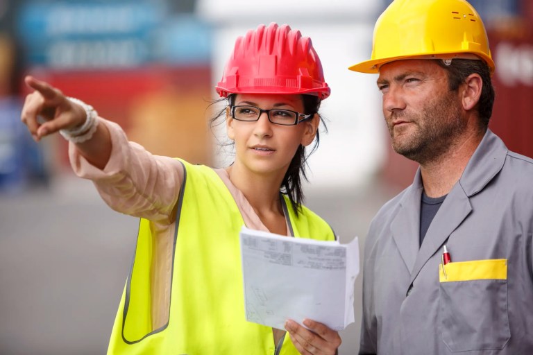 Male and female commercial six sigma inspectors analyzing quality at shipping container dock