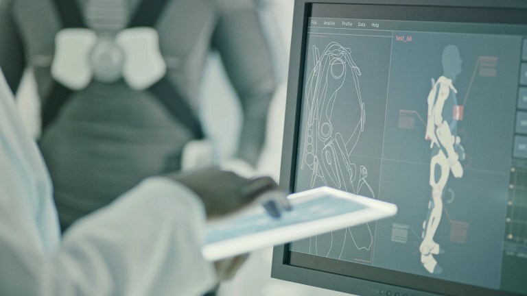 Scientist reviewing scan of powered exoskeleton in scifi concept