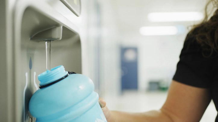Teacher refilling water bottle at fountain in hallway