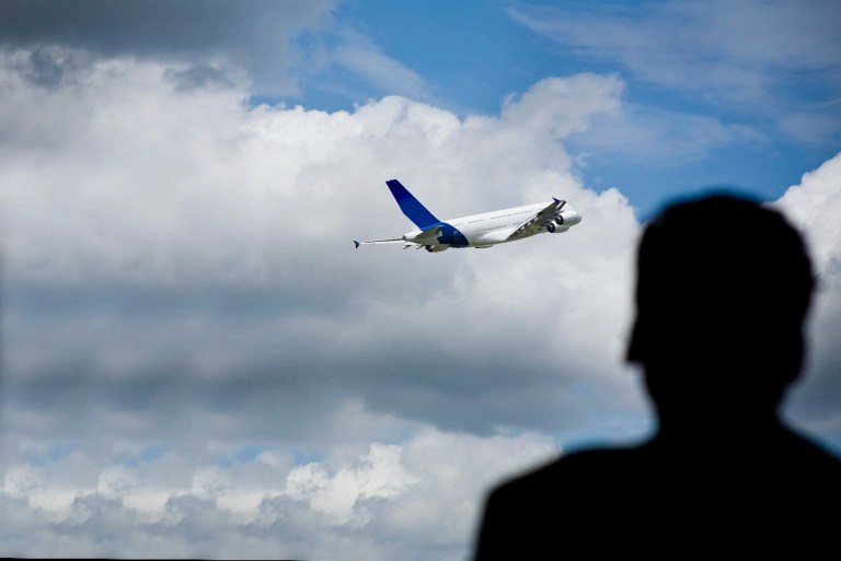 Silhouette watching AS9100 certified plane takeoff into sky