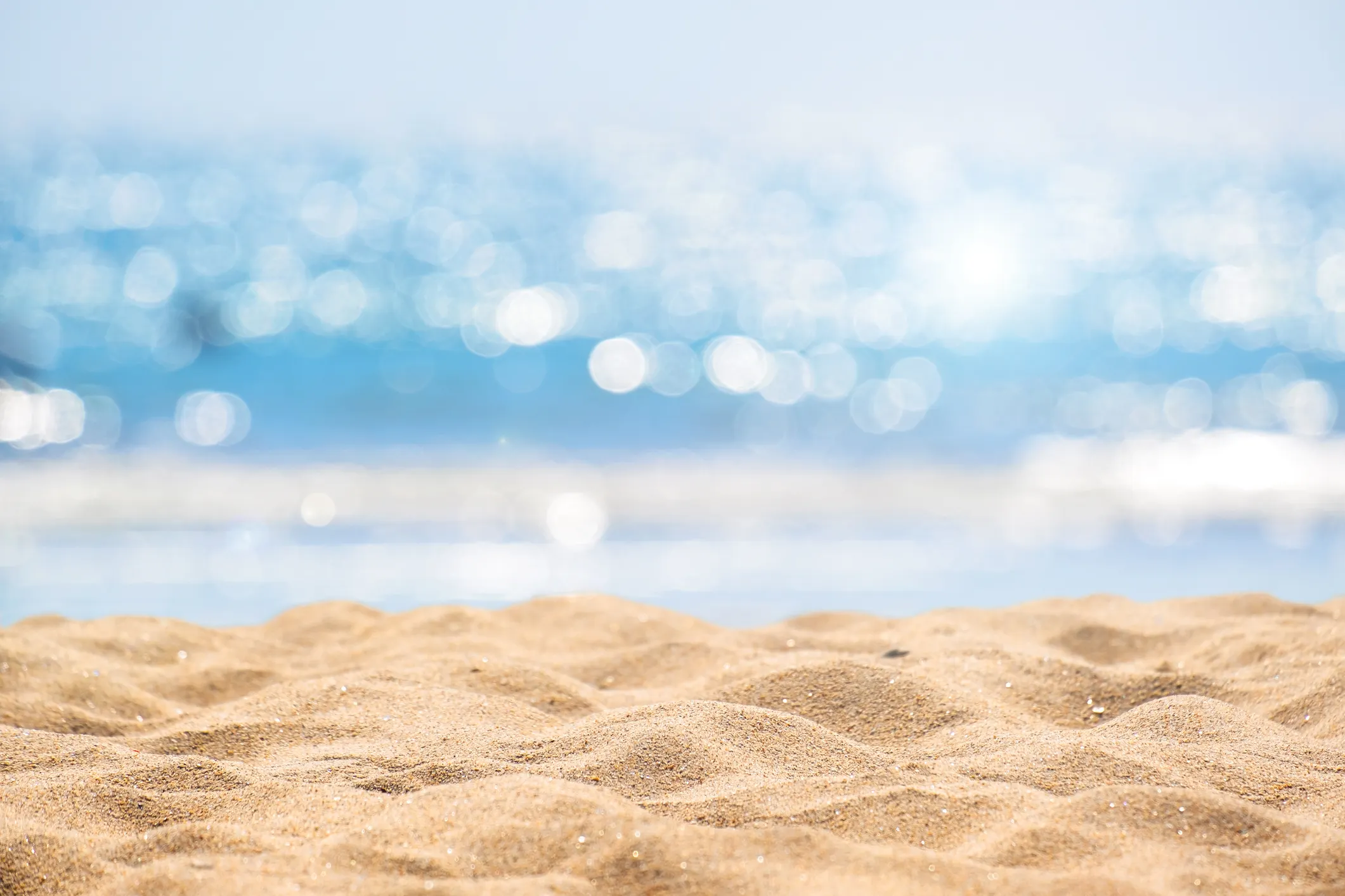 Beach sand with ocean in background sparkling