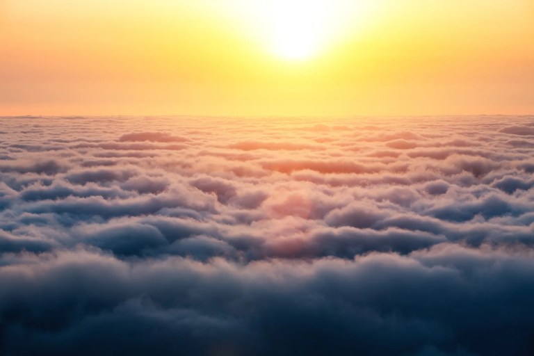 Sun shining and ready to descend from above the puffy clouds