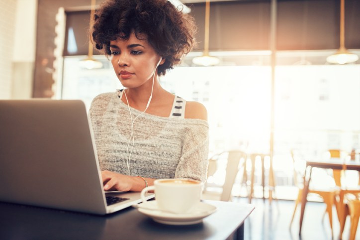 Woman at a cafe on her computer, likely leading to vision and hearing loss.