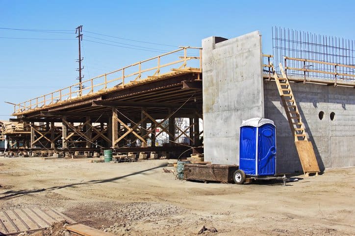 A blue porta potty as construction site bathroom adhering to ANSI Z4.3