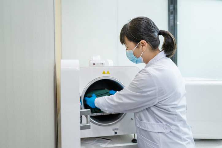 Doctor inserting used medical instruments into machine to conduct ethylene oxide sterilization.