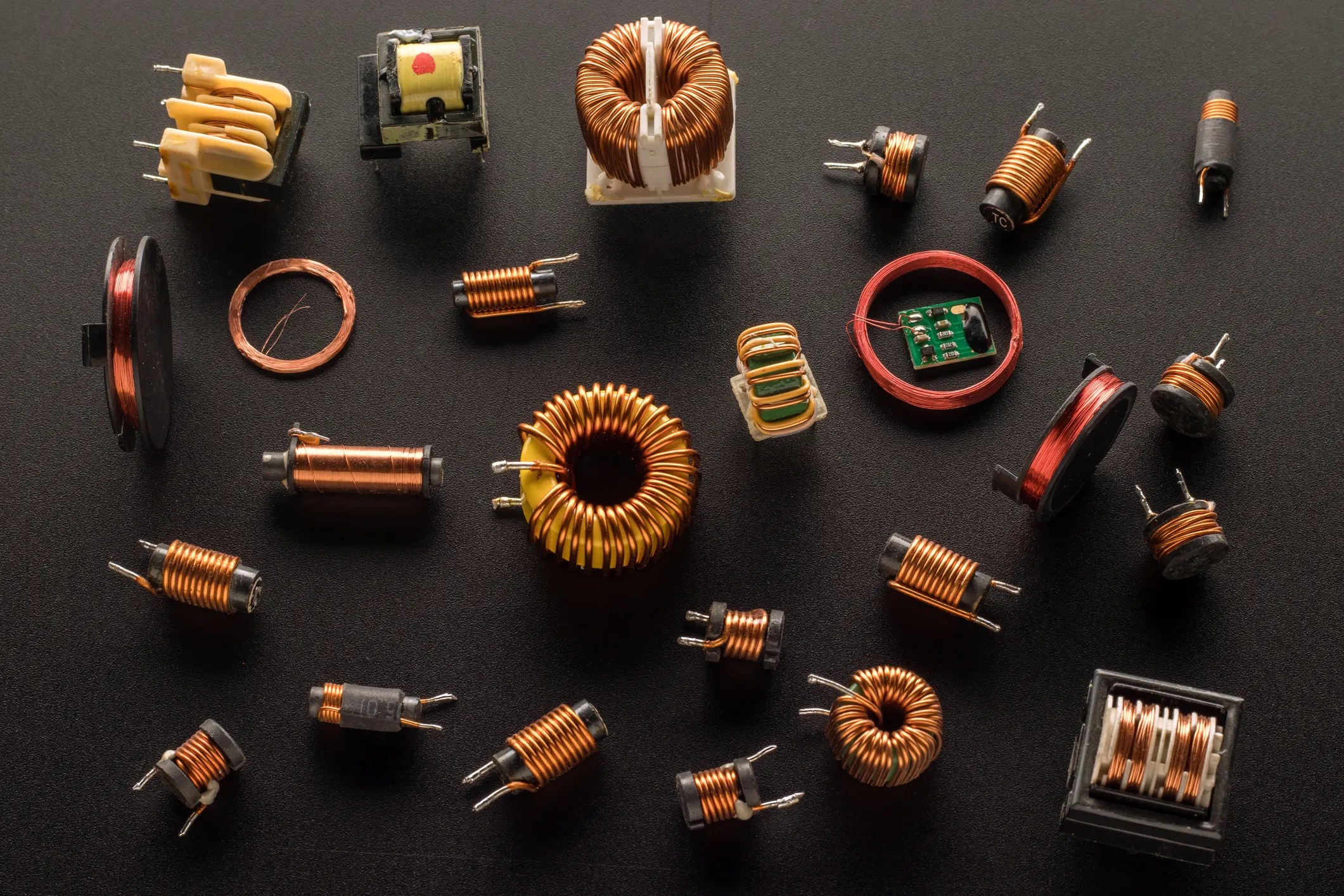 Numerous inductors with ferrite cores and wrapped in copper ANSI/NEMA MW 1000 magnetic wire on chalkboard surface