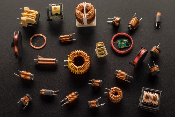 Numerous inductors with ferrite cores and wrapped in copper ANSI/NEMA MW 1000 magnetic wire on chalkboard surface