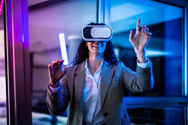 Businesswoman having fun with VR goggles in purple lit room