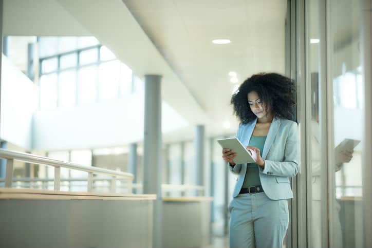 Woman in suit working on a tablet while following ISO/TS 9002:2016