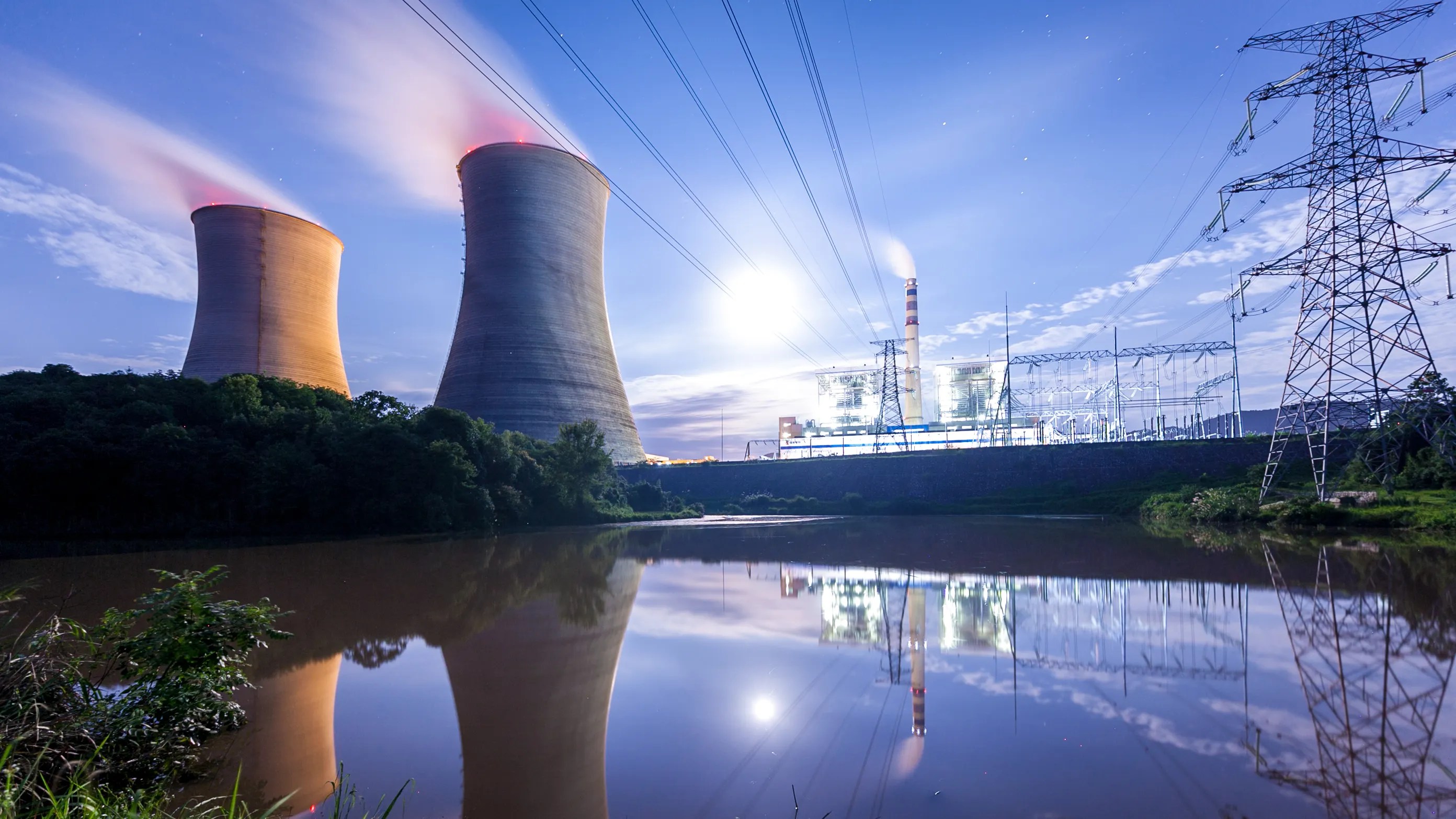 A nuclear plant beneath purple light an beside pond not ready for shutdown
