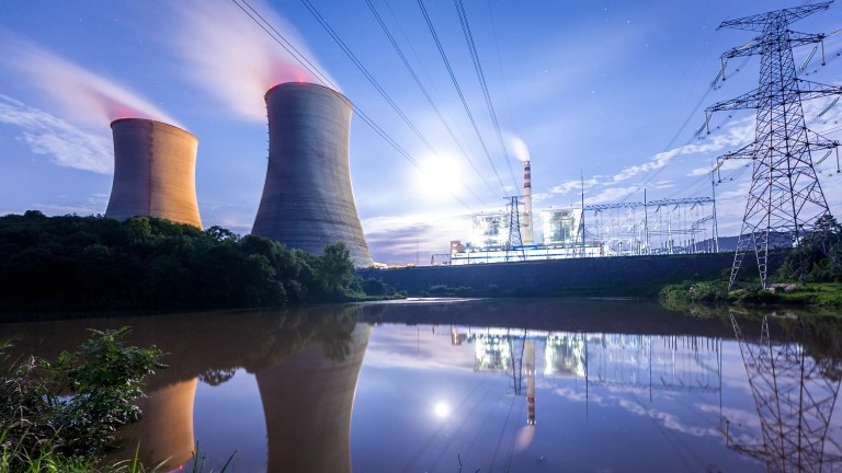 A nuclear plant beneath purple light an beside pond not ready for shutdown