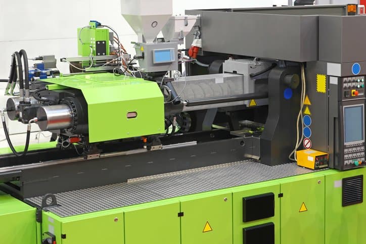 A green ANSI/PLASTICS B151.1-2017 injection molding machine