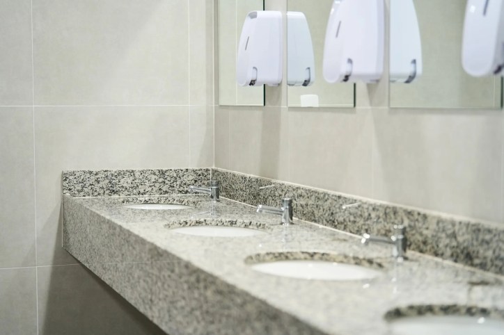 Sinks lined up on granite in ANSI/PSAI Z4.1-2016 workplace bathroom