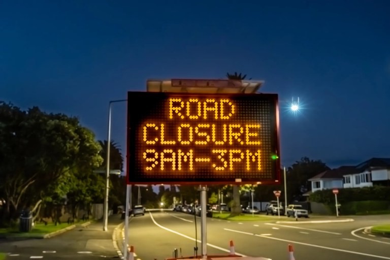 Road closure 9AM-3PM dynamic message sign (DMS) on side of road at night