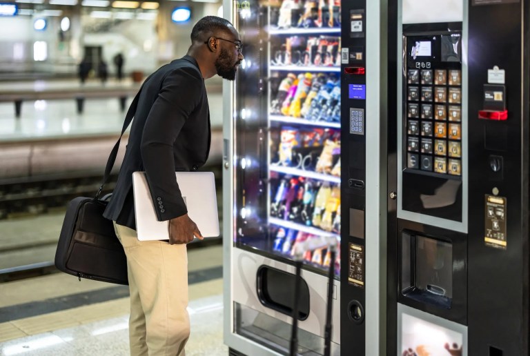 Man holding laptop and looking into ANSI/ASHRAE Standard 32.1 vending machine