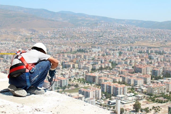 Worker overlooking city and contemplating ANSI/ASSE Z359.2-2017 fall protection